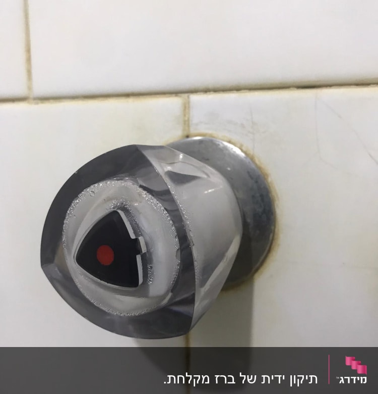 ידית ברז מים עם סימון אדום על קיר קרמיקה